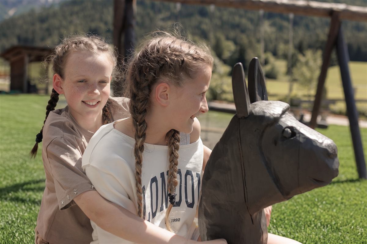 Geschwister spielen auf der Wiese, Dolomiten im Hintergrund